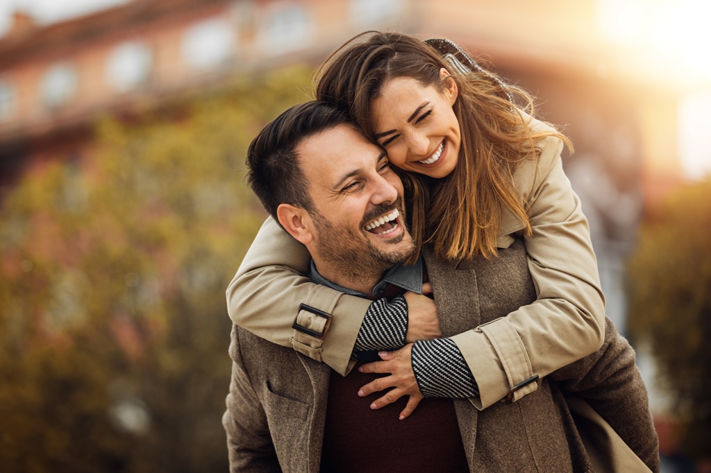 Smiling man giving a happy woman a piggy back ride as she wraps her arms around his shoulders